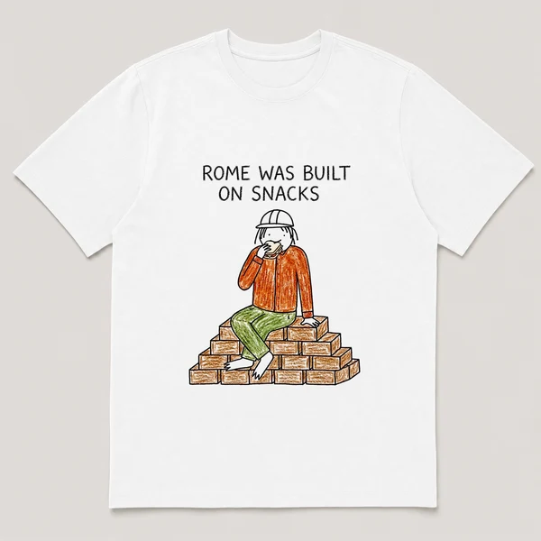 Front view of a White Tee printed with bricklayer sits on a brick pile eating a sandwich mid-shift and the caption ROME WAS BUILT ON SNACKS