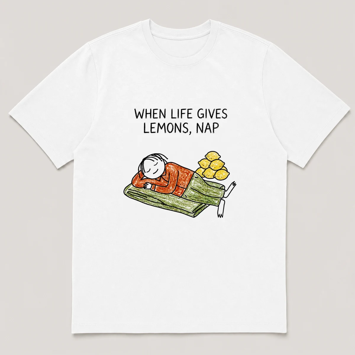 Front view of a White Tee printed with guy naps on a blanket with a pile of lemons stacked beside him and the caption WHEN LIFE GIVES LEMONS, NAP, White front view