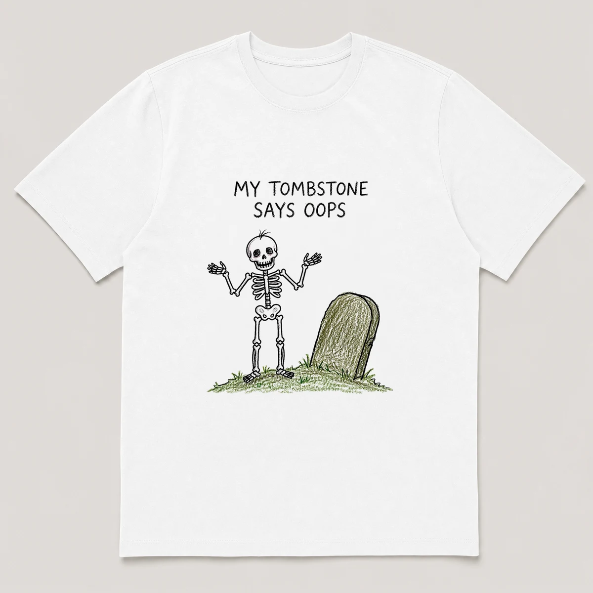 Front view of a White Tee printed with skeleton shrugs beside a lopsided tombstone on a small grassy mound and the caption MY TOMBSTONE SAYS OOPS, White front view