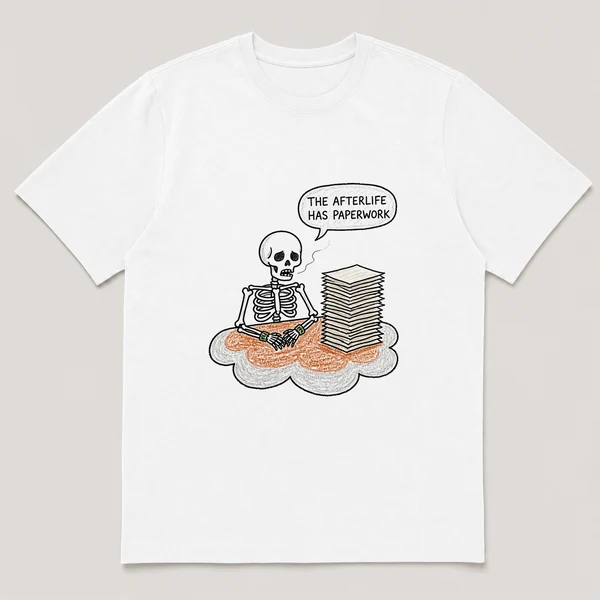 Front view of a White Tee printed with skeleton at a cloud desk sighs over a tall stack of blank papers and the caption THE AFTERLIFE HAS PAPERWORK