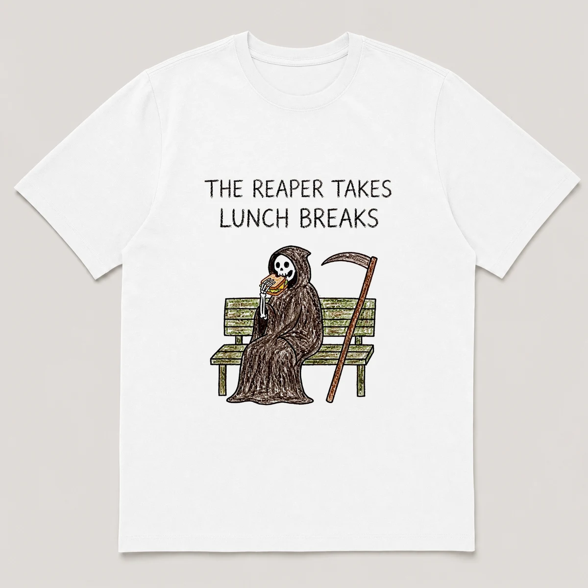 Front view of a White Tee printed with cloaked reaper eats a sandwich on a park bench with its scythe leaning nearby and the caption THE REAPER TAKES LUNCH BREAKS, White front view