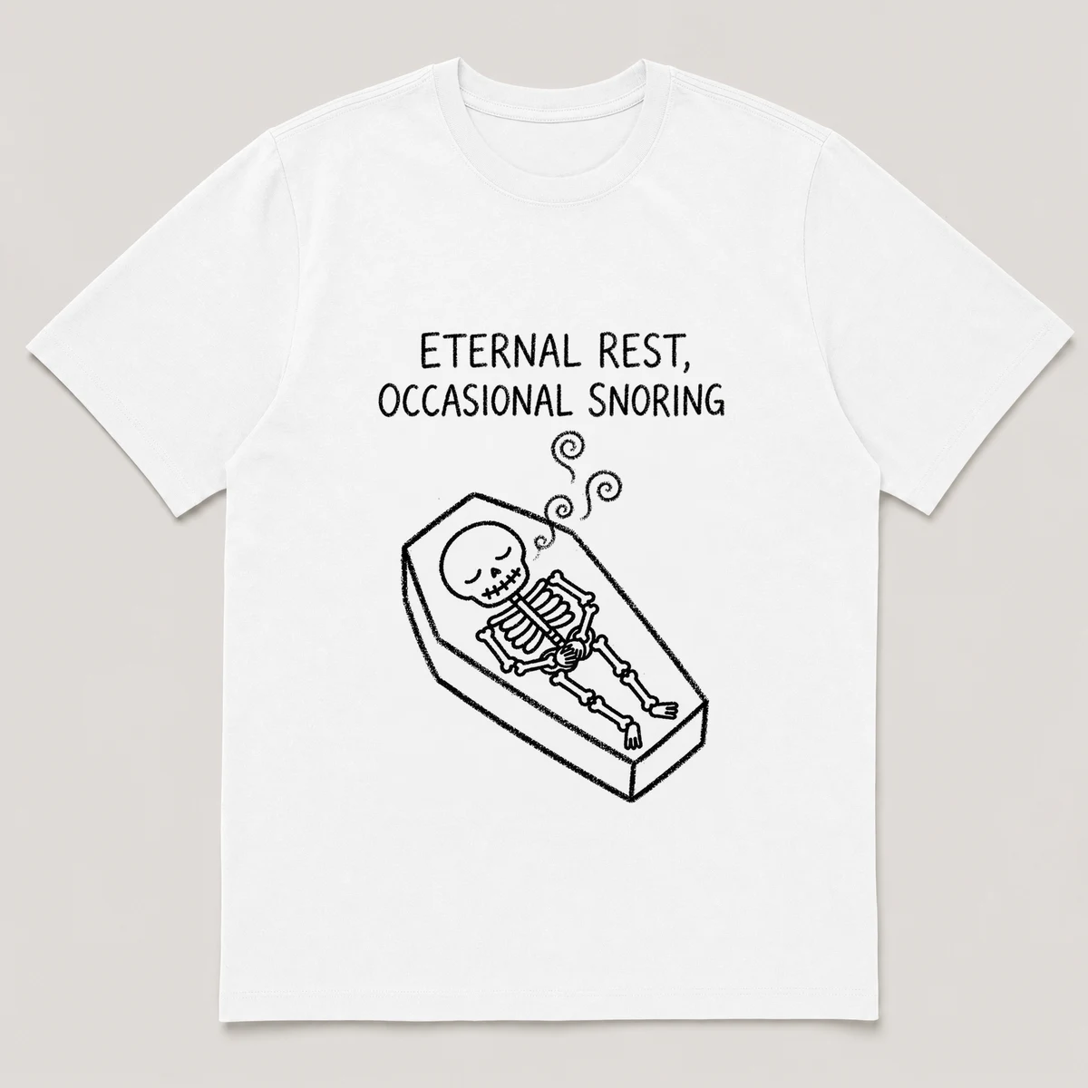 Front view of a White Tee printed with skeleton naps in a coffin with three wobbly sleep curls drifting up and the caption ETERNAL REST, OCCASIONAL SNORING, White front view
