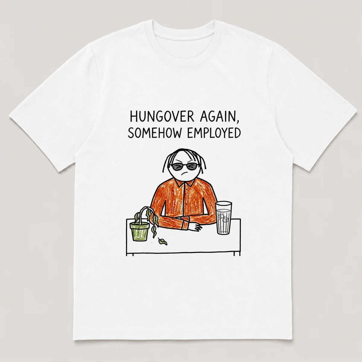 Front view of a White Tee printed with squinting guy in sunglasses sits at a desk with a wilted plant and a tall water glass and the caption HUNGOVER AGAIN, SOMEHOW EMPLOYED, White front view