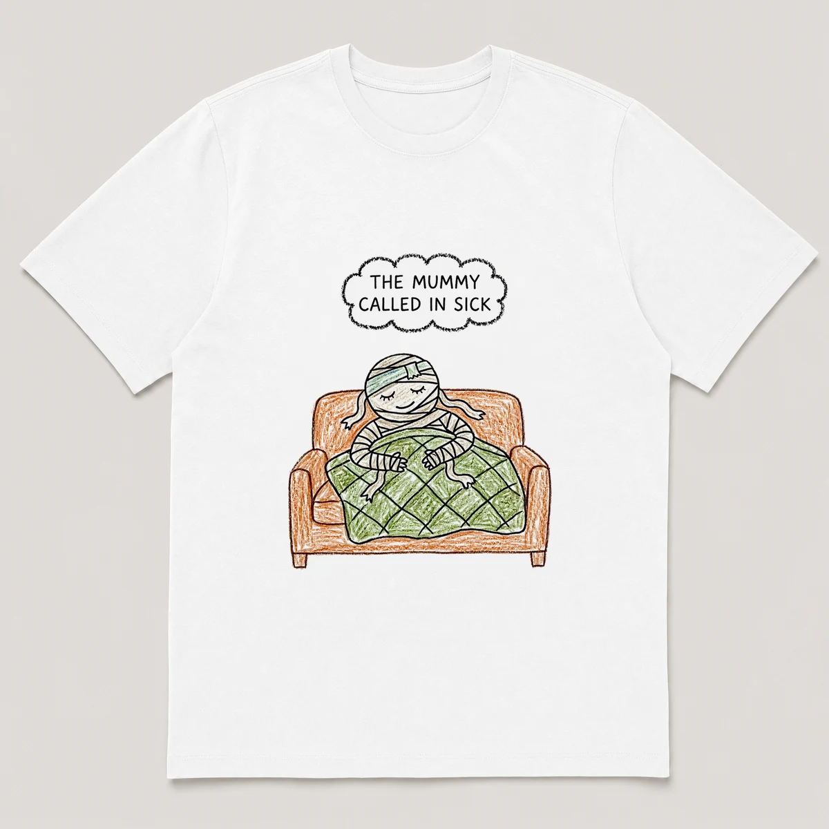 Front view of a White Tee printed with bandaged mummy naps on a couch under a quilt with a cold cloth on its head and the caption THE MUMMY CALLED IN SICK, White front view