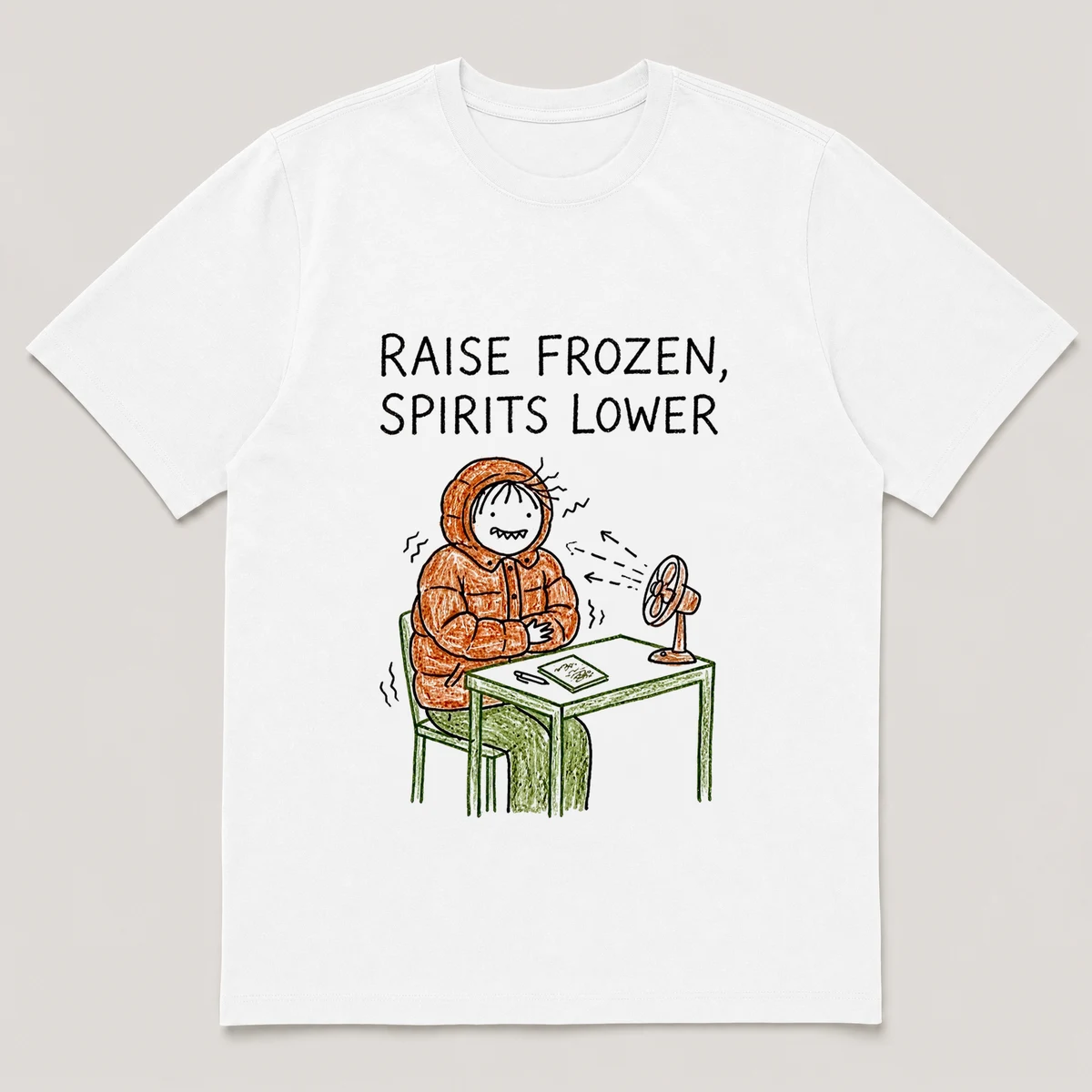 Front view of a White Tee printed with guy in a winter coat shivers at his desk while a small fan blows on him and the caption RAISE FROZEN, SPIRITS LOWER, White front view